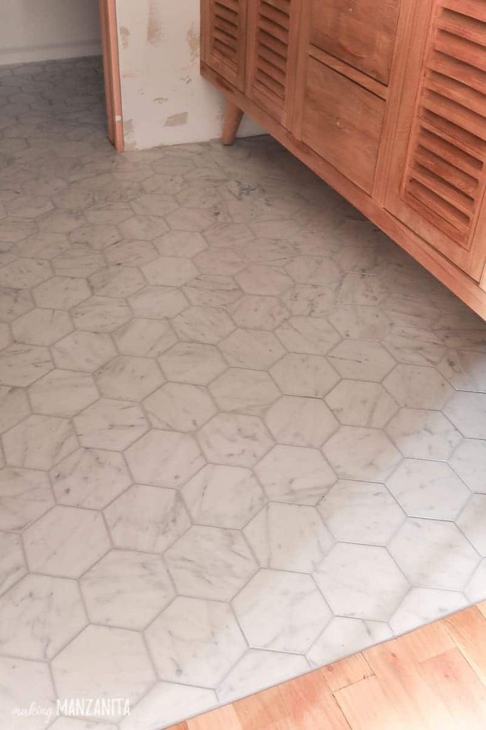 Hexagon marble tile flooring in front of wooden vanity in bathroom under renovation