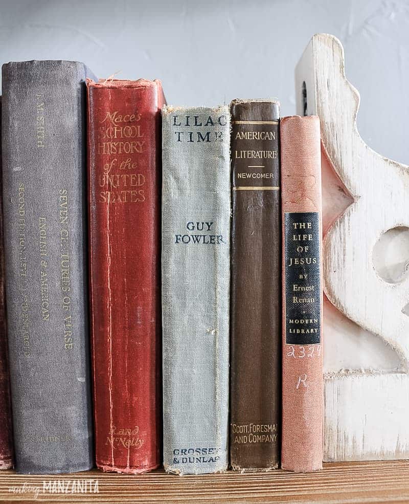 Vintage books on a shelf with worn covers and vintage corbel used as a bookend