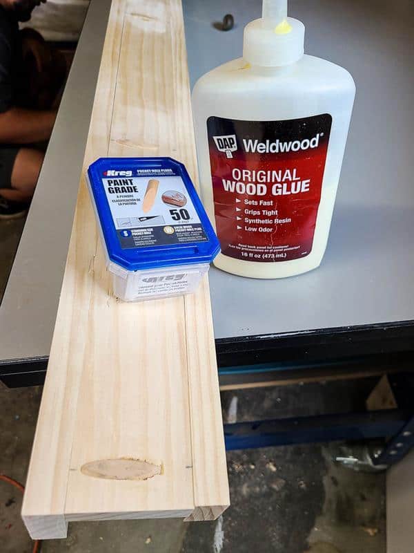 A photograph showing a piece of paint-grade wood along with a bottle of wood glue.