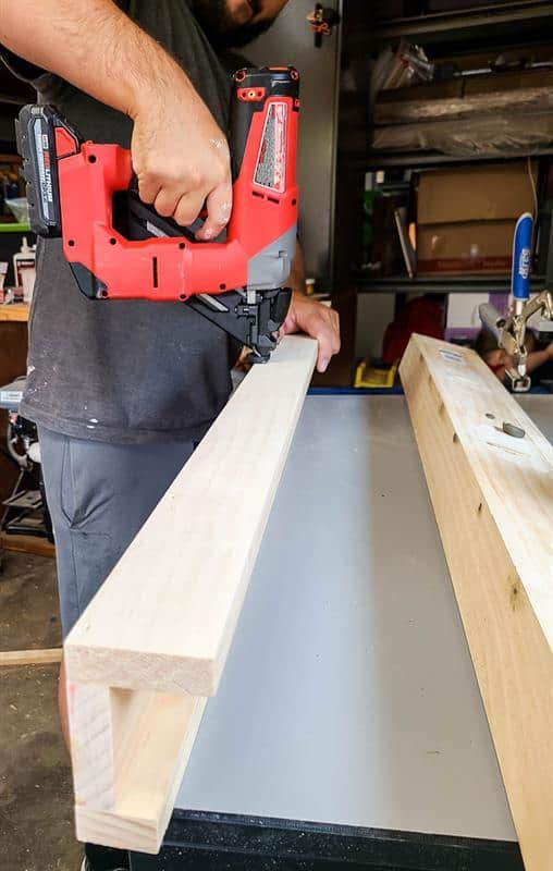 A man is securing the front and back pieces of a picture ledge together.