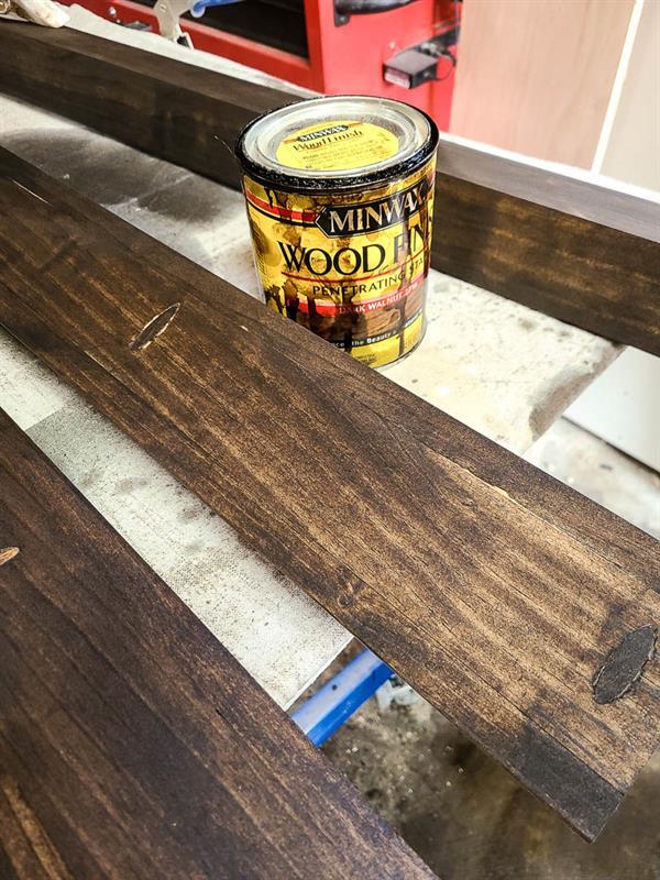 A picture featuring wood alongside a container of wood stain, both intended for use in creating a picture ledge.