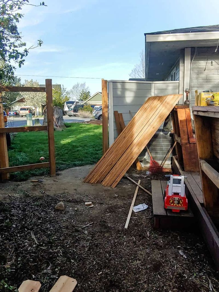 Scrap woods, toy truck and unused home items at the wooden fence before a gate is built.