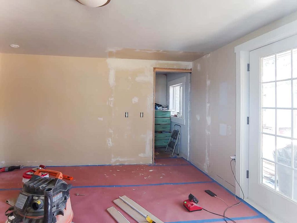 Master bedroom and small closet before the makeover with rough drywall patches and red rosin paper over flooring