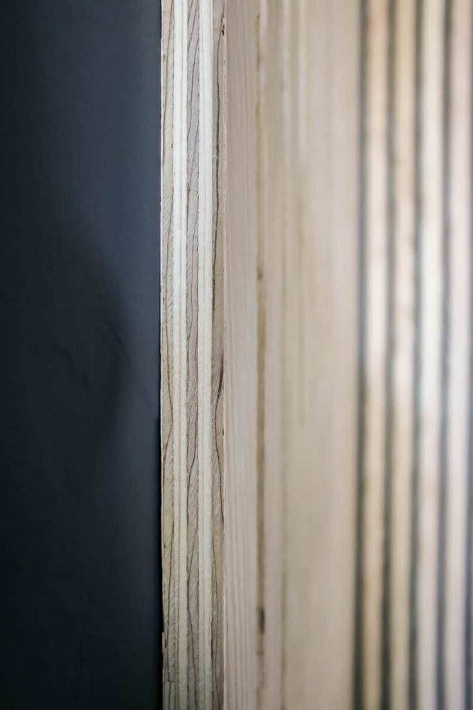 Close up of slat of wood nailed to the wall with plywood edge exposed