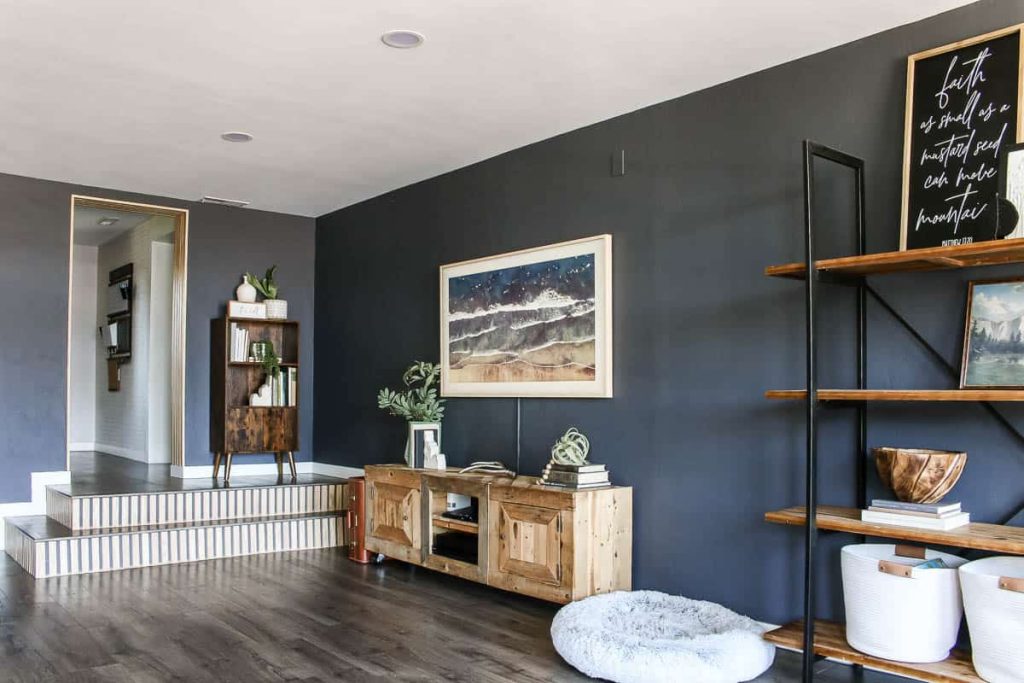 After image of new steps, gray laminate flooring, industrial bookshelf round dog bed, TV console made with pallet wood and Samsung Frame TV hanging on wall on modern boho living room.