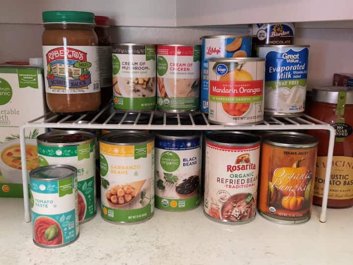 Food cans and tins on the shelf of a store cupboard Stock Photo