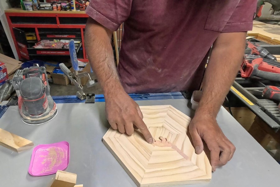 The man fills the gap with wood filler to complete the Chicknic Table.